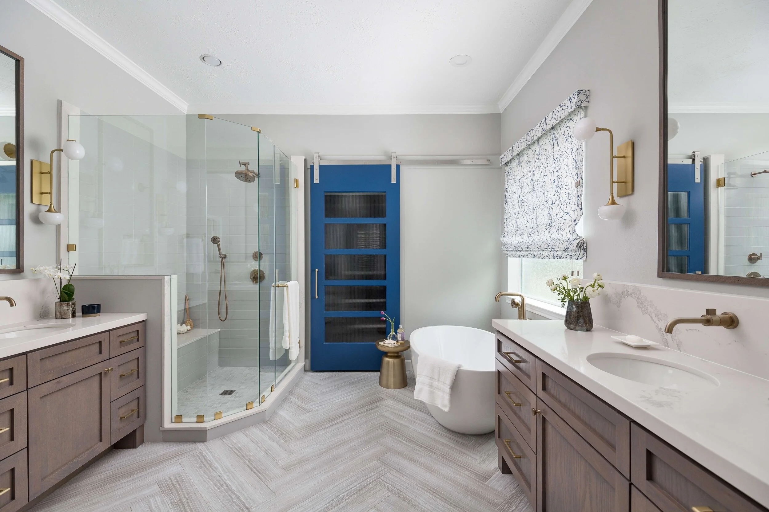 Elegant bathroom with glass shower, freestanding tub, and blue barn door.