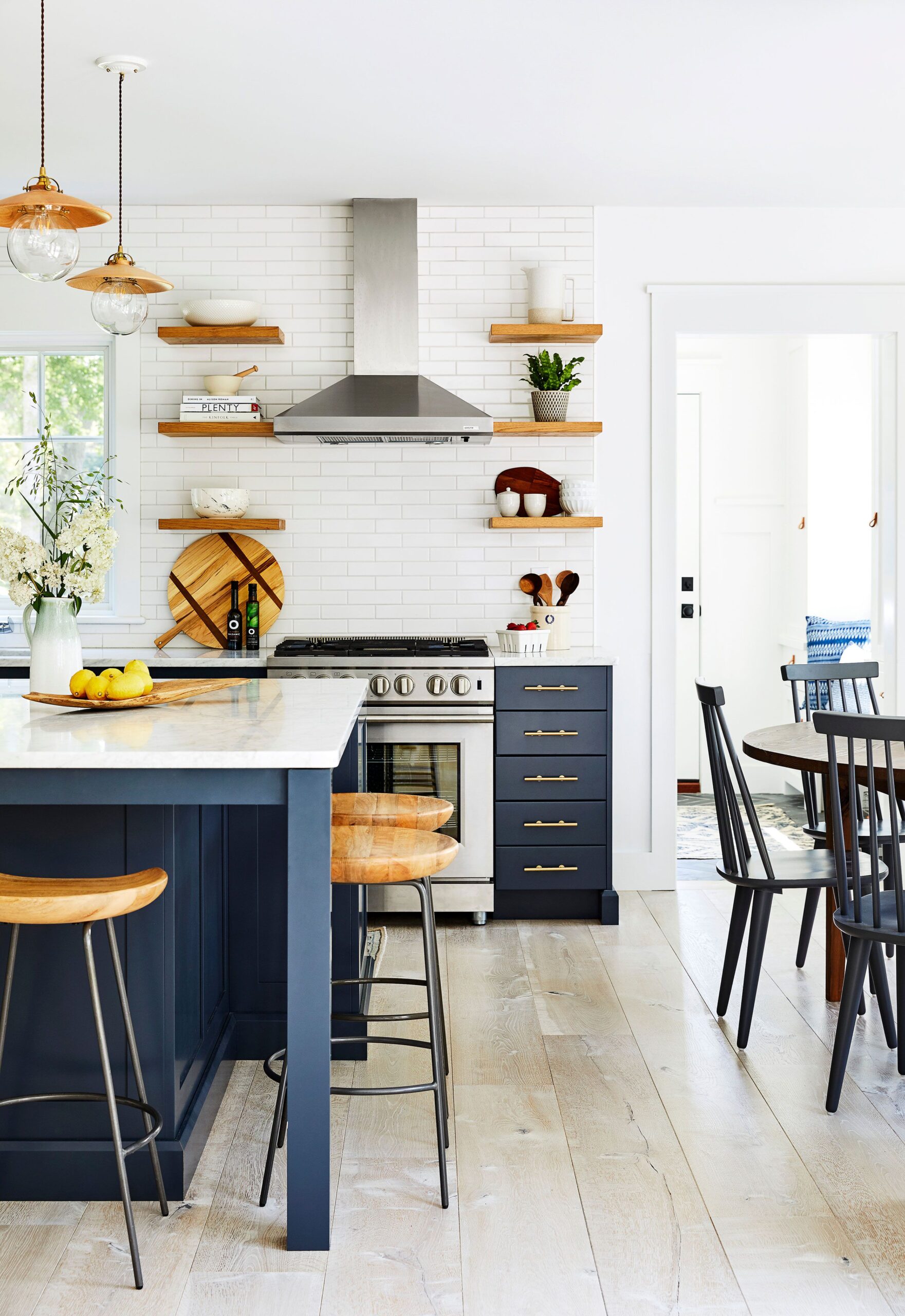 Bright kitchen with navy blue cabinets, open wood shelving, and white subway tile backsplash.