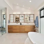 Modern bathroom with wooden vanity, freestanding tub, and walk-in glass shower