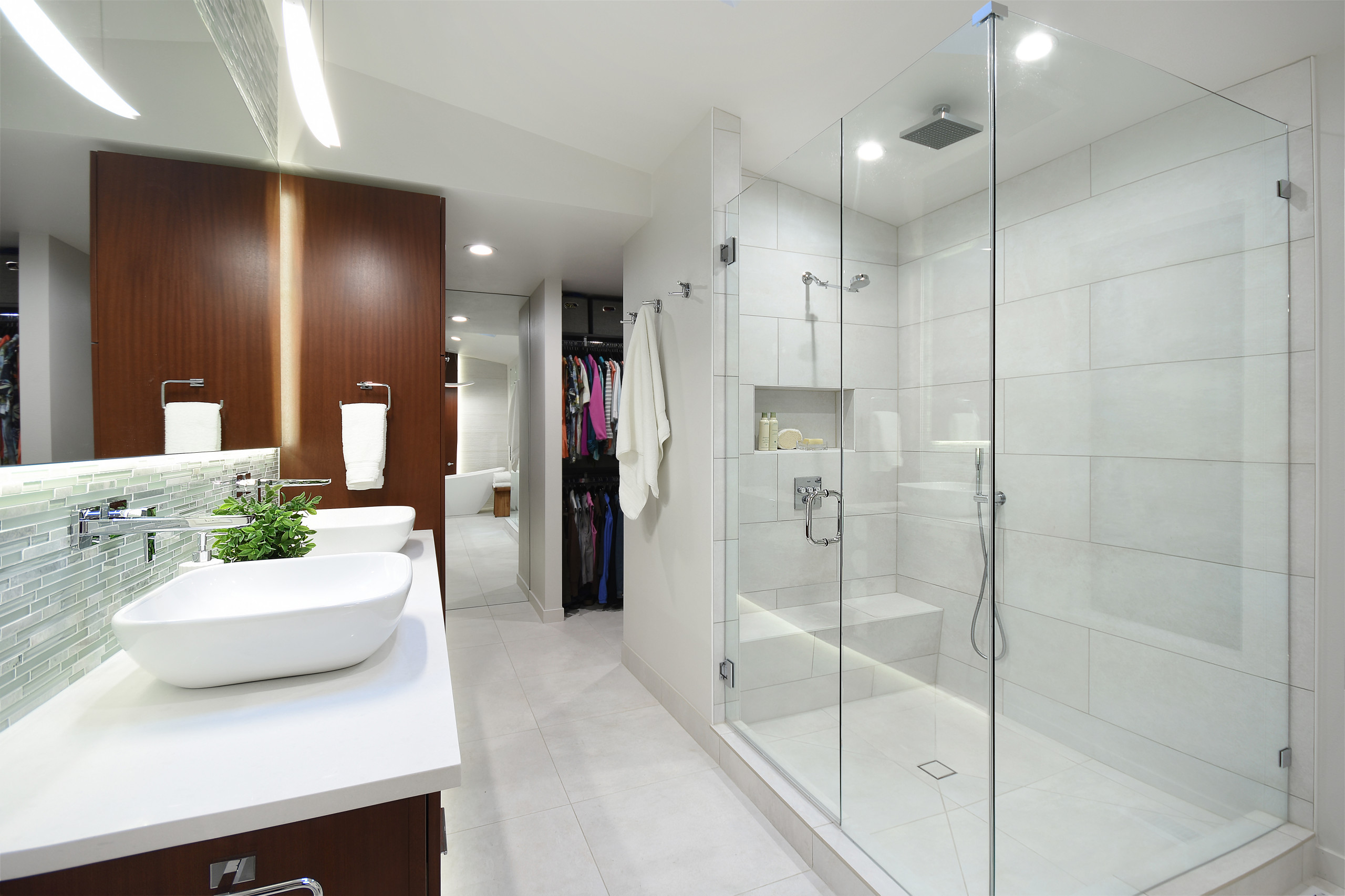 Modern bathroom with glass shower enclosure, vessel sinks, and wood accents.