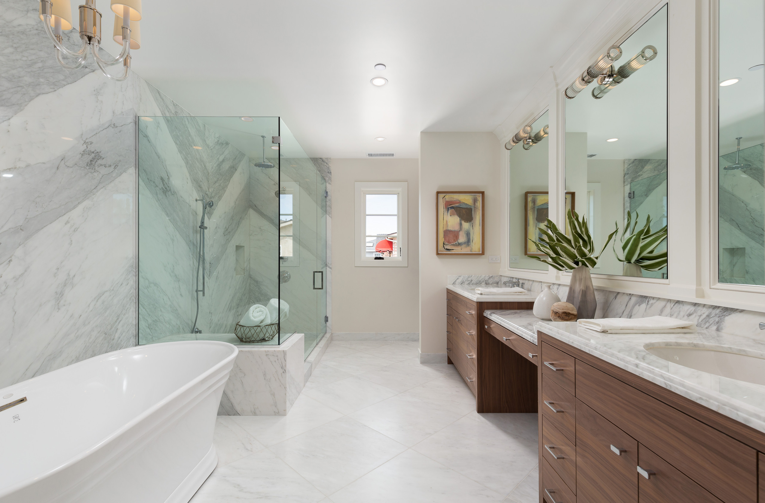 Luxurious bathroom with marble finishes, glass shower, and freestanding bathtub.