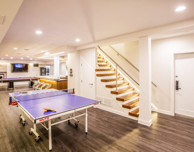 Modern basement recreation room with game tables and bar area