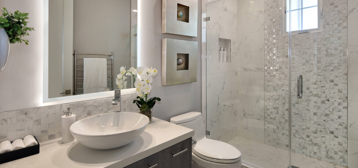 Contemporary bathroom with lighted vanity mirror, vessel sink, and glass-enclosed shower.
