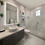 Contemporary bathroom with lighted vanity mirror, vessel sink, and glass-enclosed shower.
