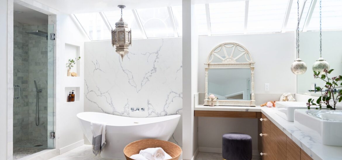 Luxurious bathroom with skylights, freestanding white tub, marble walls, and Moroccan-inspired decor.