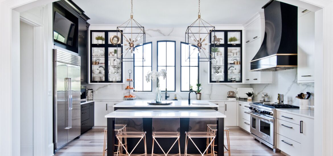 Modern black and white kitchen with gold accents and geometric pendant lighting.