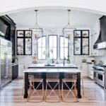 Modern black and white kitchen with gold accents and geometric pendant lighting.