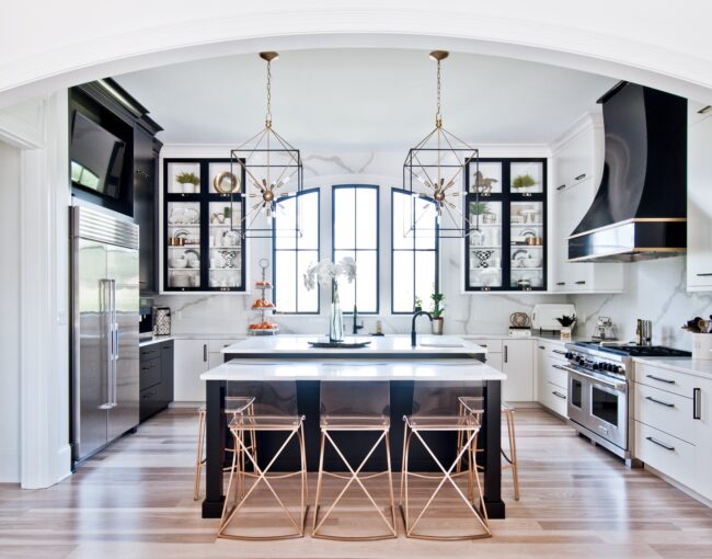 Modern black and white kitchen with gold accents and geometric pendant lighting.