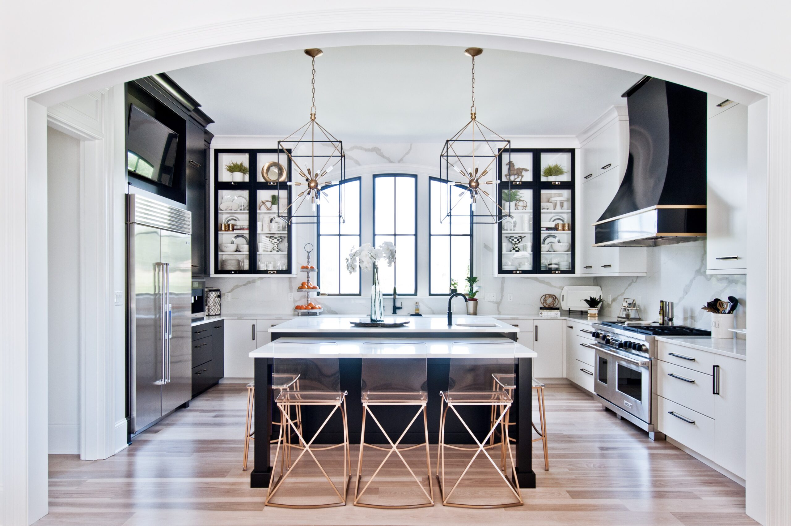 Modern black and white kitchen with gold accents and geometric pendant lighting.