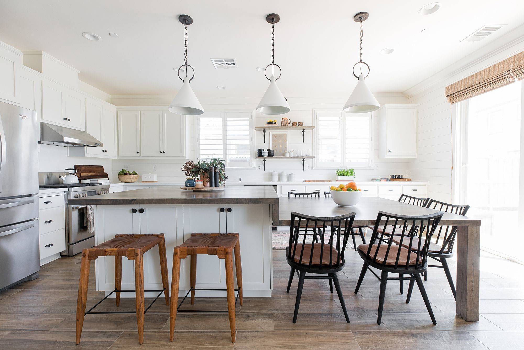 Bright farmhouse-style kitchen with white cabinetry, wood island countertop, and a dining table set.
