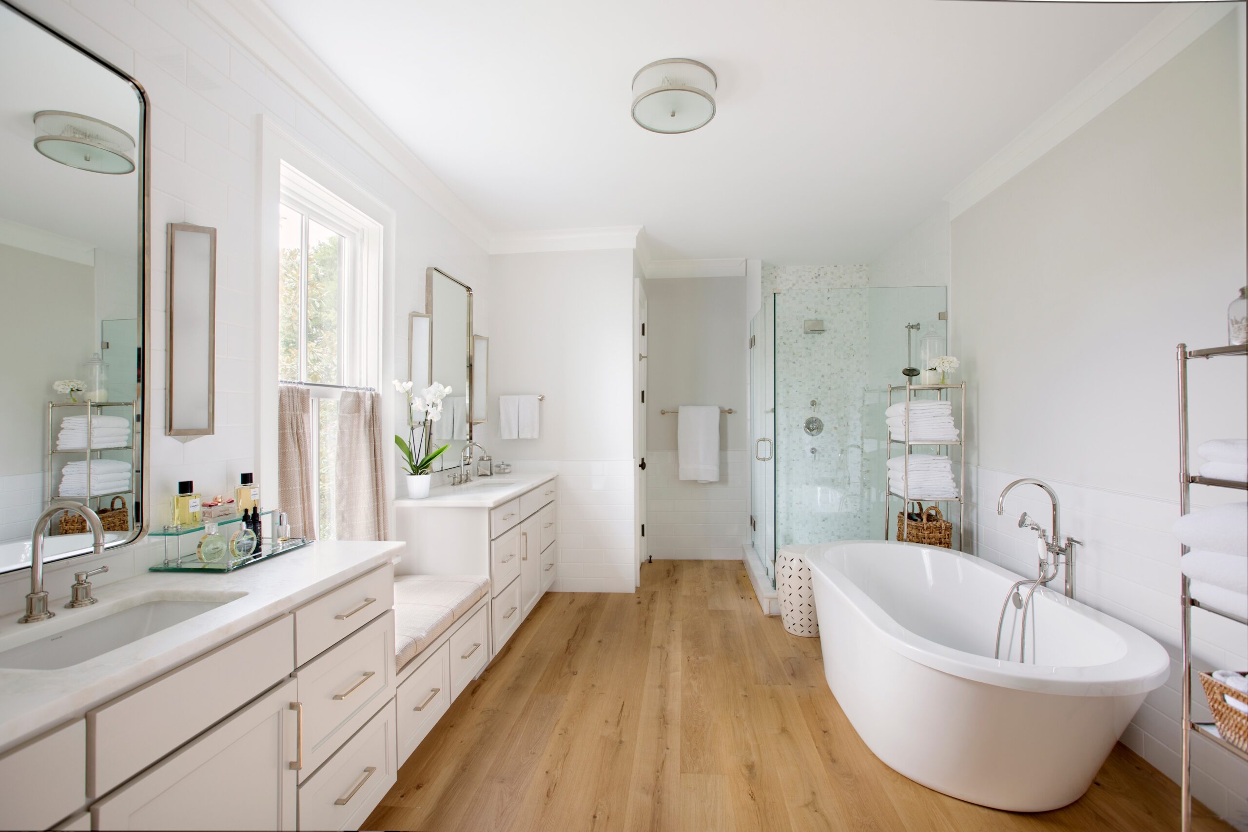 Bright bathroom with freestanding tub, glass shower, and double vanity.