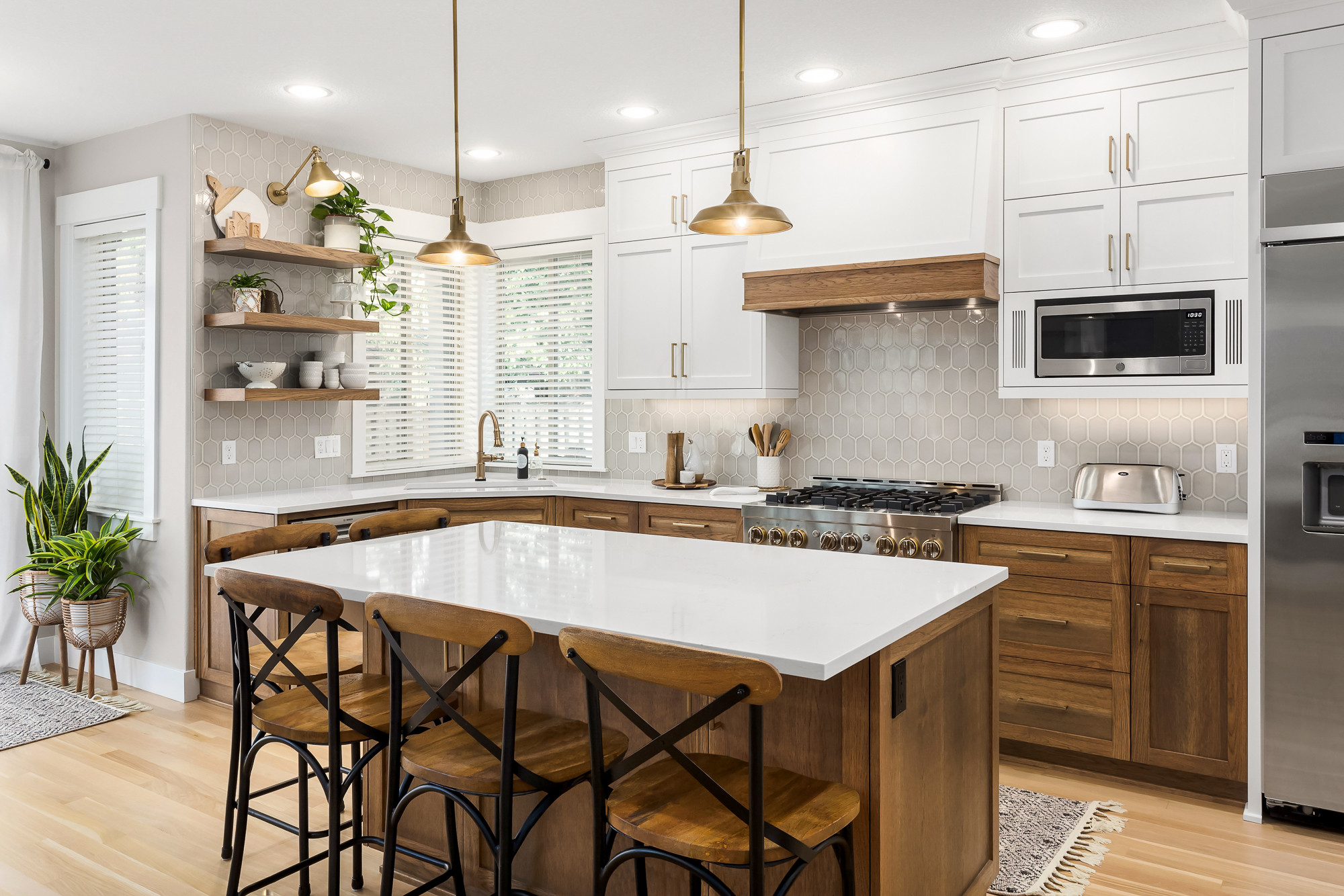 Modern kitchen with white upper cabinets, warm wood lower cabinets, a white quartz island, and hexagonal tile backsplash.