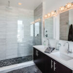 Contemporary bathroom with glass-enclosed shower, double vanity, and modern lighting.