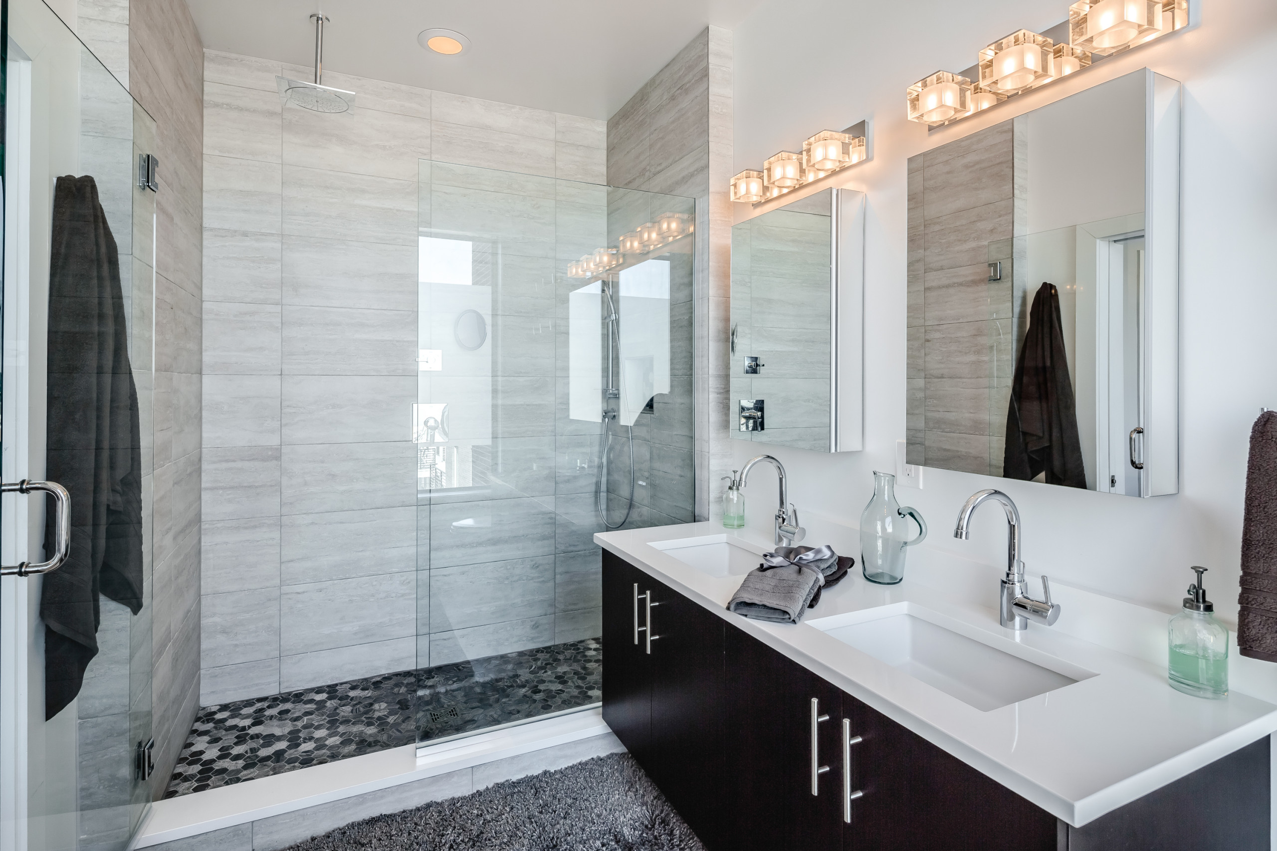 Contemporary bathroom with glass-enclosed shower, double vanity, and modern lighting.