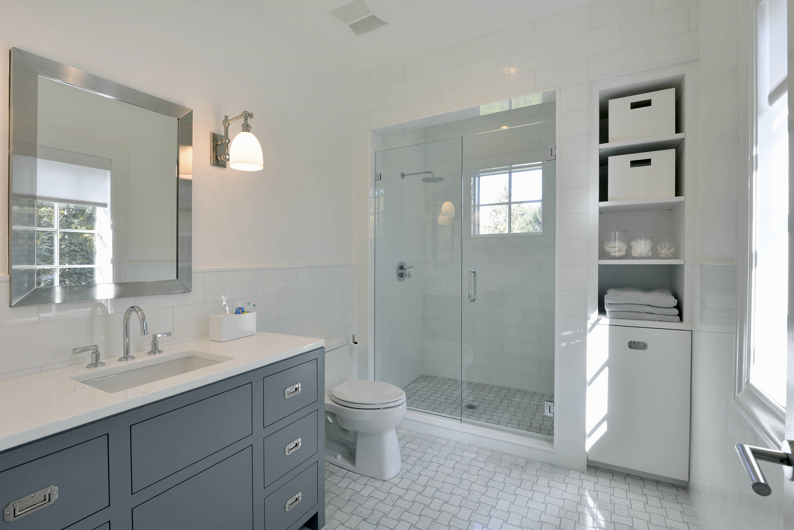Bright contemporary bathroom with glass-enclosed shower and blue vanity.