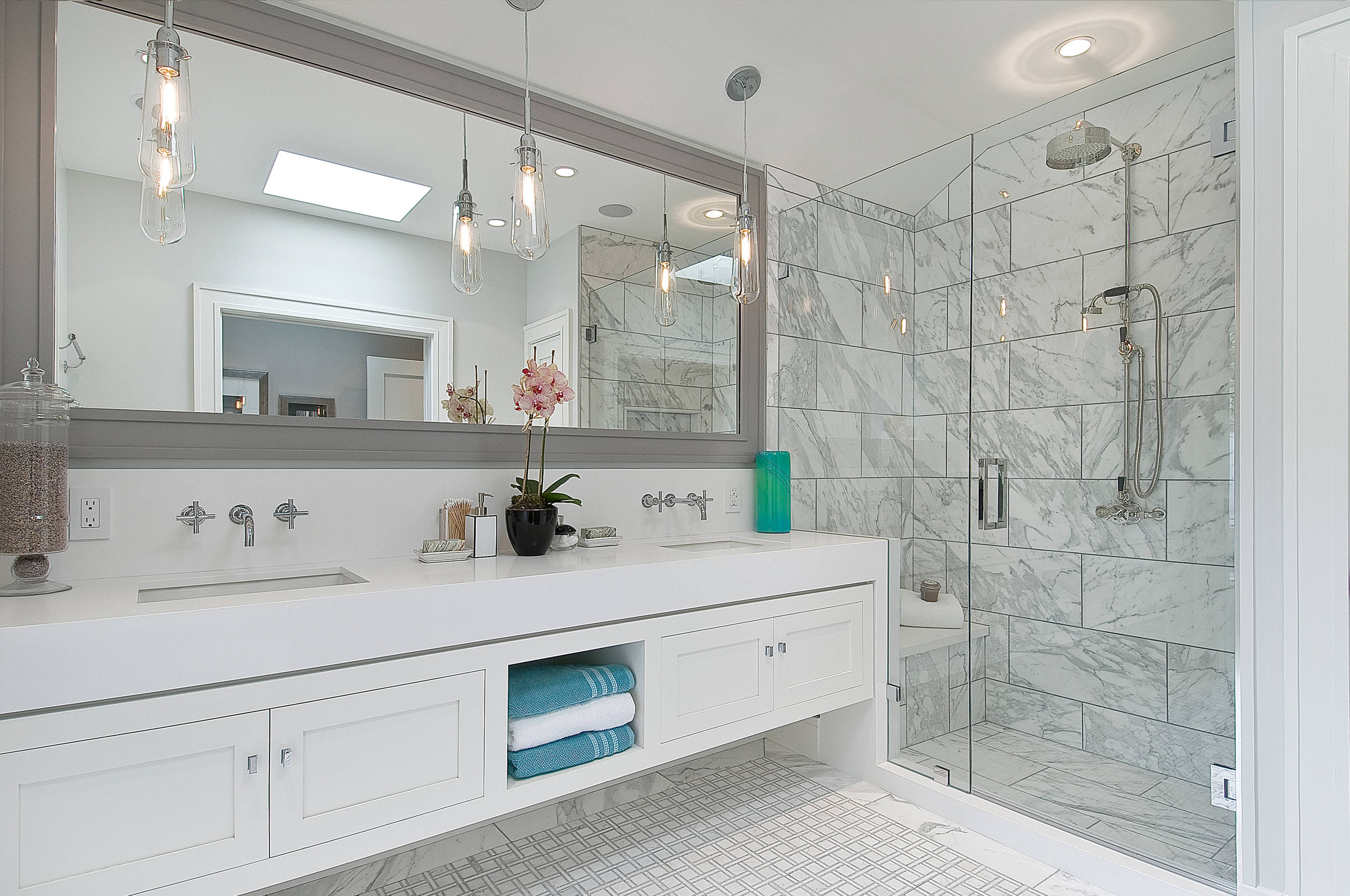 Elegant white bathroom with marble-tiled walk-in shower and floating vanity.