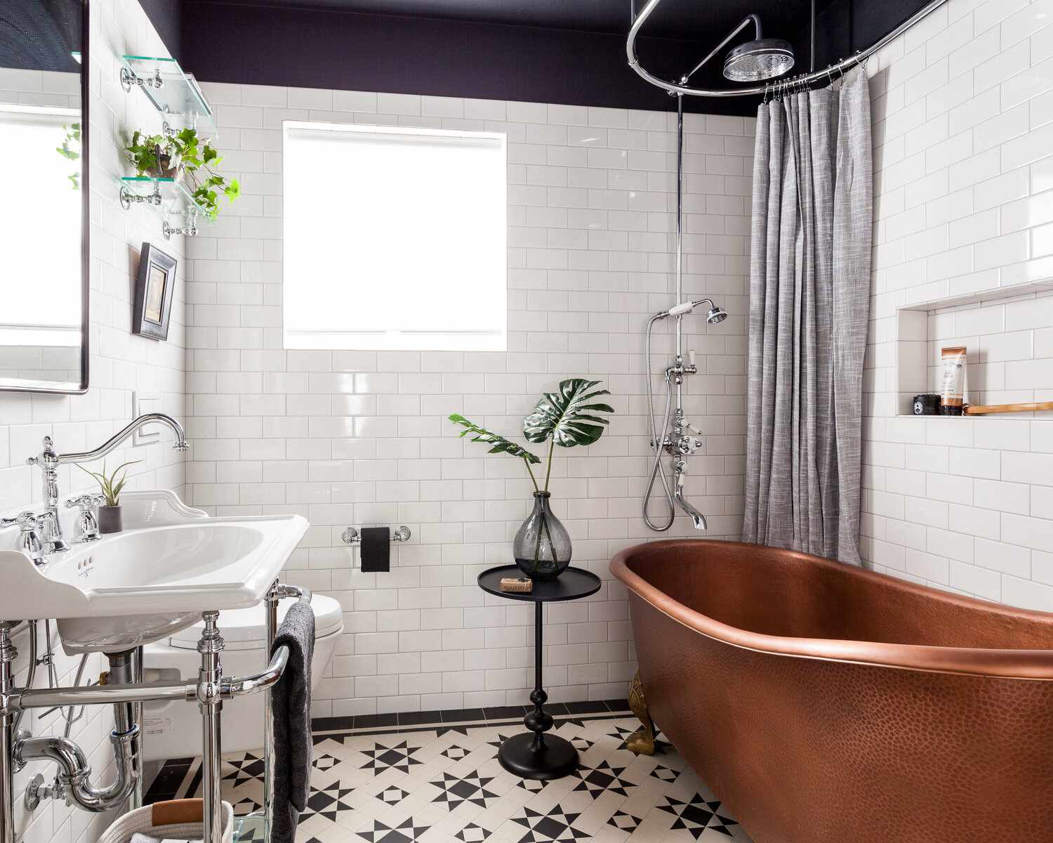 Vintage bathroom with copper bathtub, patterned floor tiles, and white subway wall tiles.