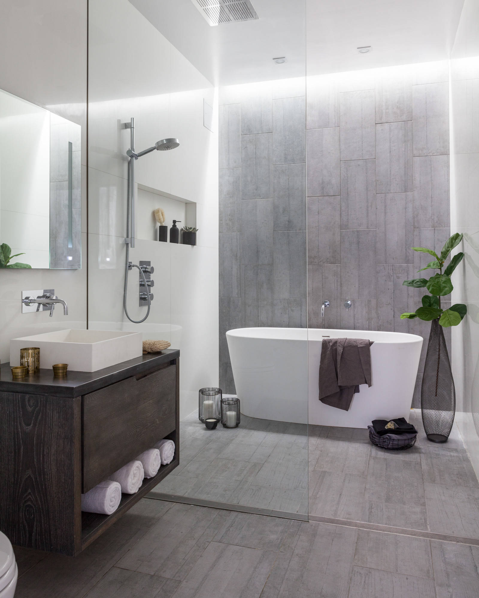 Minimalist bathroom with freestanding bathtub, grey tile walls, and floating vanity.