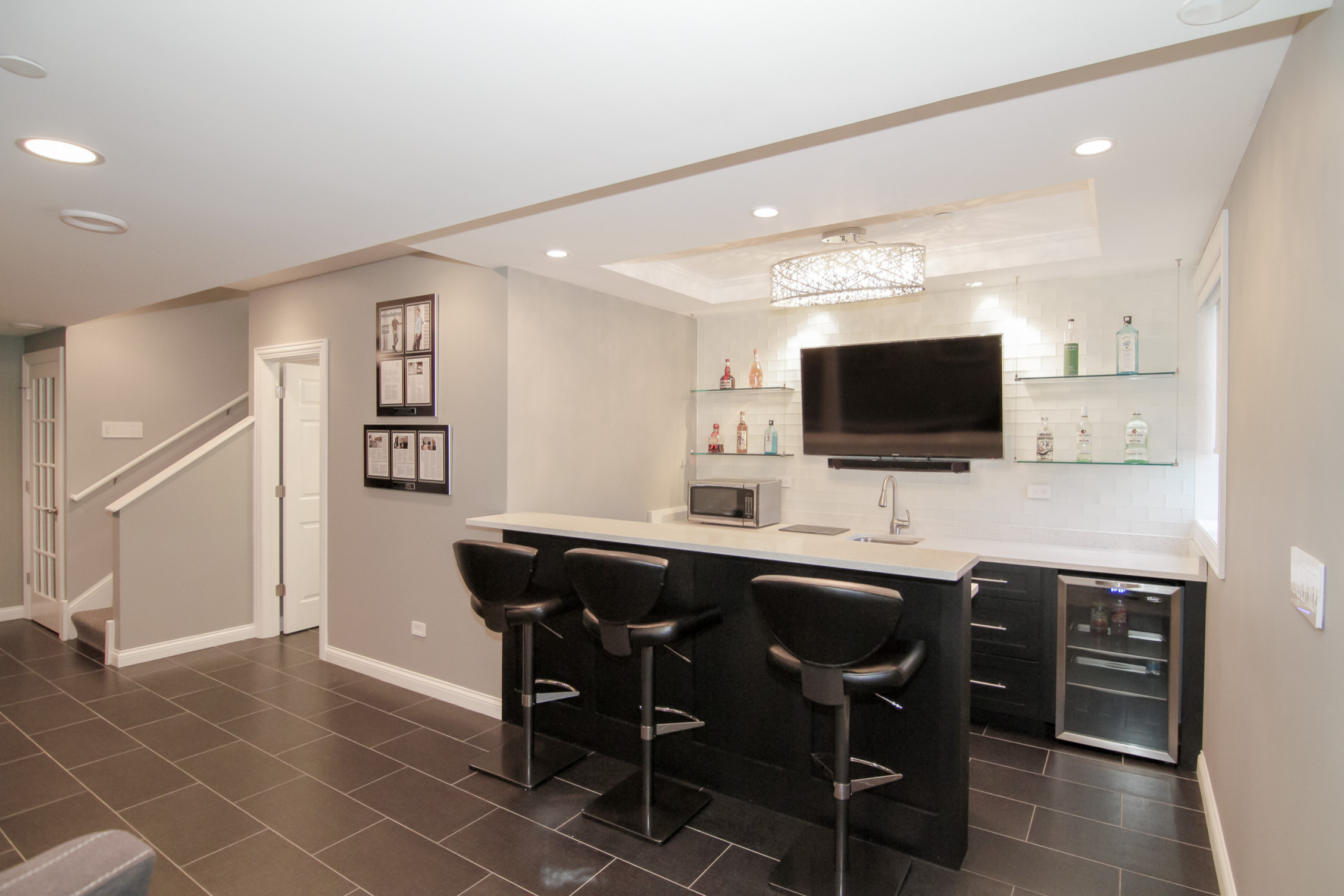Modern basement bar with black stools and white countertop