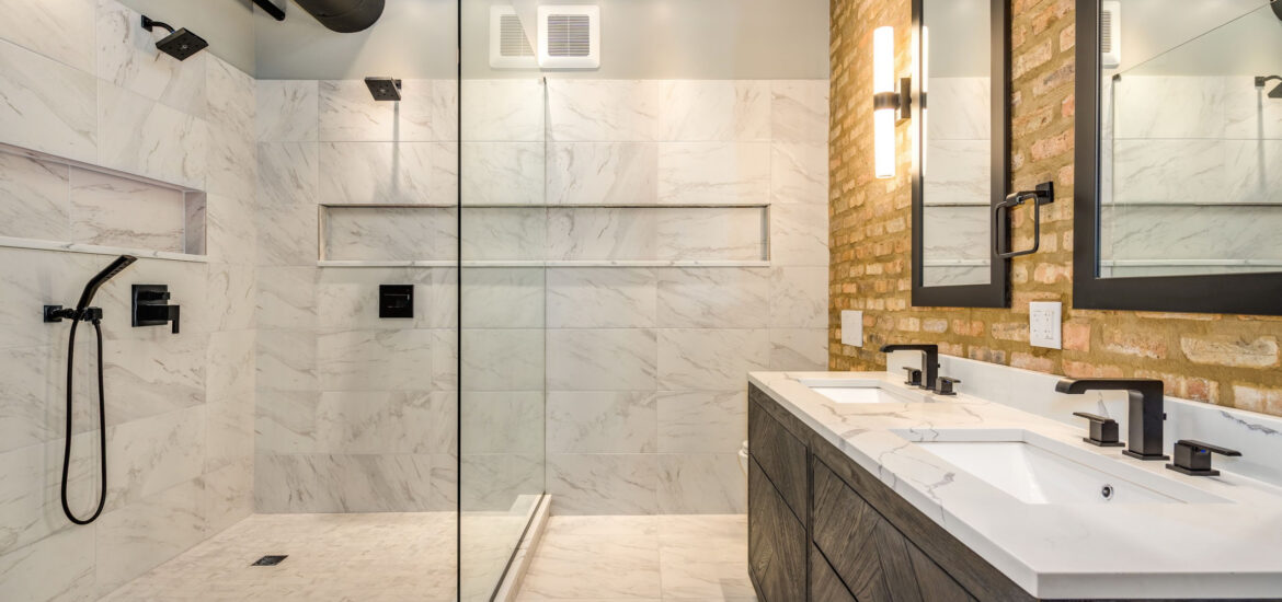 Industrial bathroom with marble tile shower, exposed brick wall, and double vanity.
