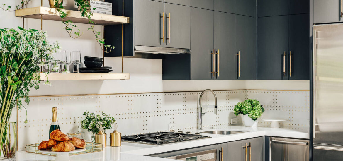 Modern kitchen with dark cabinetry, open gold shelving, and a white quartz peninsula.