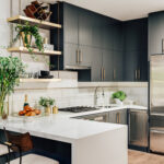 Modern kitchen with dark cabinetry, open gold shelving, and a white quartz peninsula.