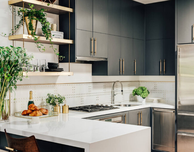 Modern kitchen with dark cabinetry, open gold shelving, and a white quartz peninsula.