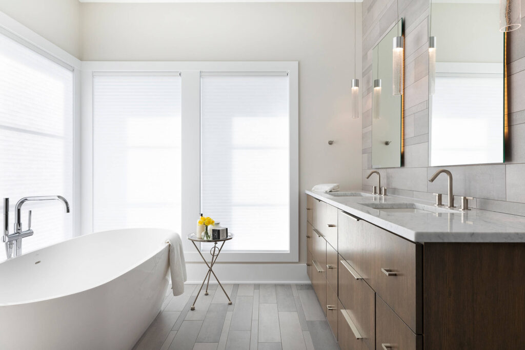 Minimalist bathroom with freestanding tub, double sink vanity, and natural light