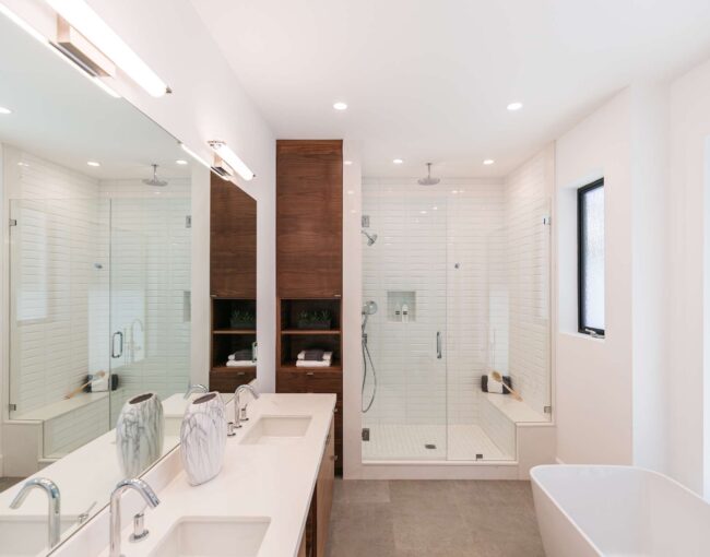 Modern bathroom with double shower, wooden cabinetry, and freestanding bathtub.