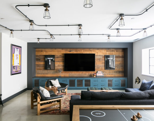 Modern basement media room with large TV, wood accent wall, and sports memorabilia.