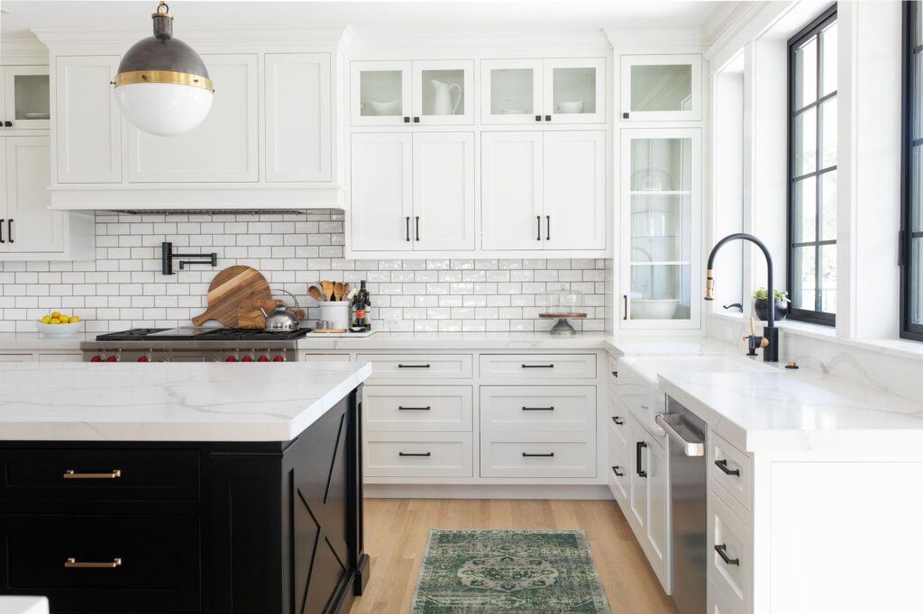 Bright farmhouse-style kitchen with white cabinetry, black island, and subway tile backsplash.