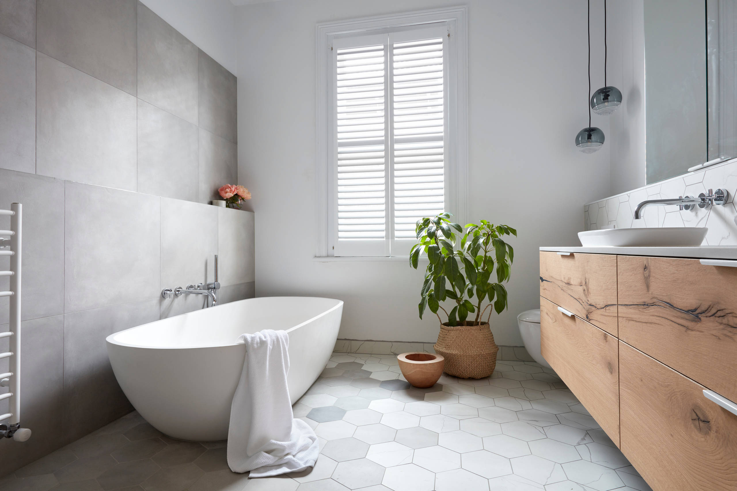 Scandinavian-inspired bathroom with freestanding bathtub and natural wood vanity.