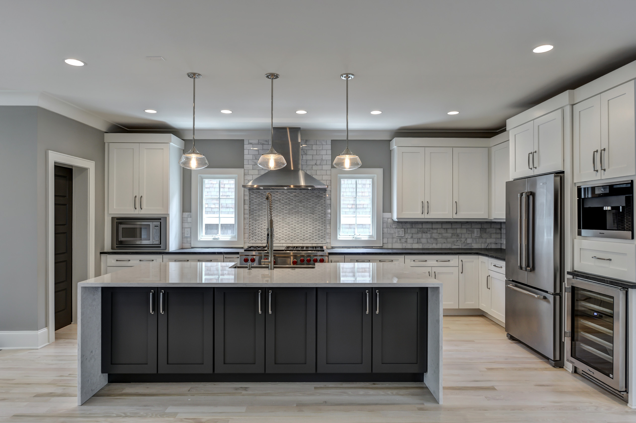 Contemporary kitchen with a large island featuring dark cabinetry and white marble countertop.