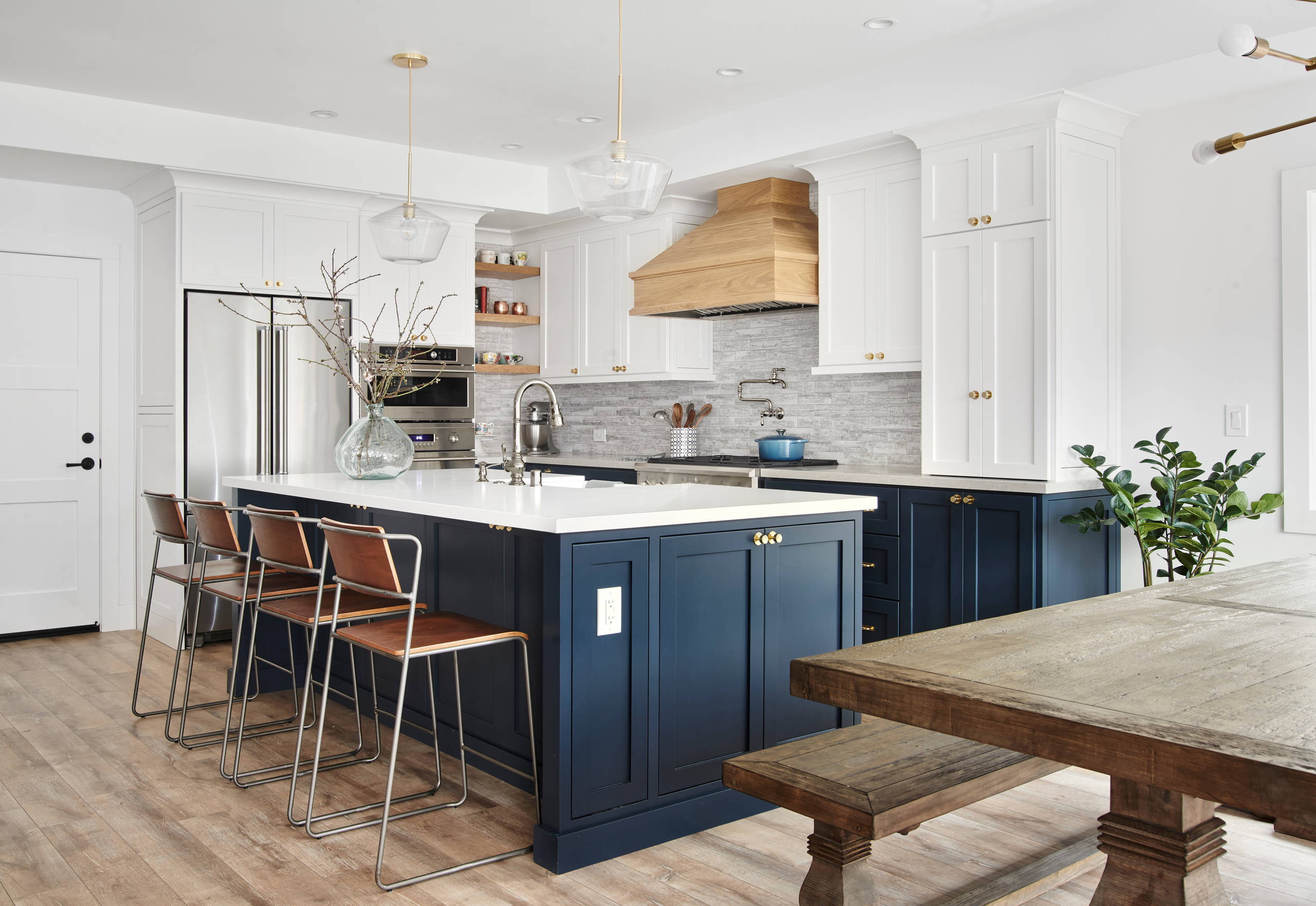 Modern two-tone kitchen with navy blue lower cabinets, white upper cabinets, and a large central island.