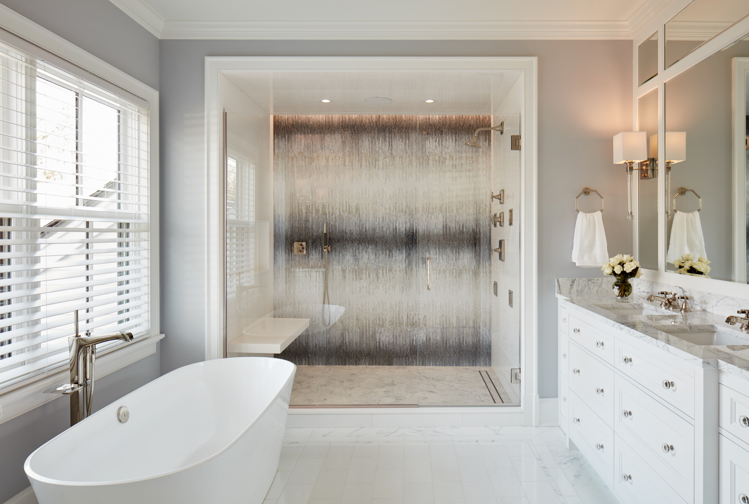 Elegant bathroom with freestanding bathtub, marble vanity, and luxury walk-in shower with mosaic tile wall.