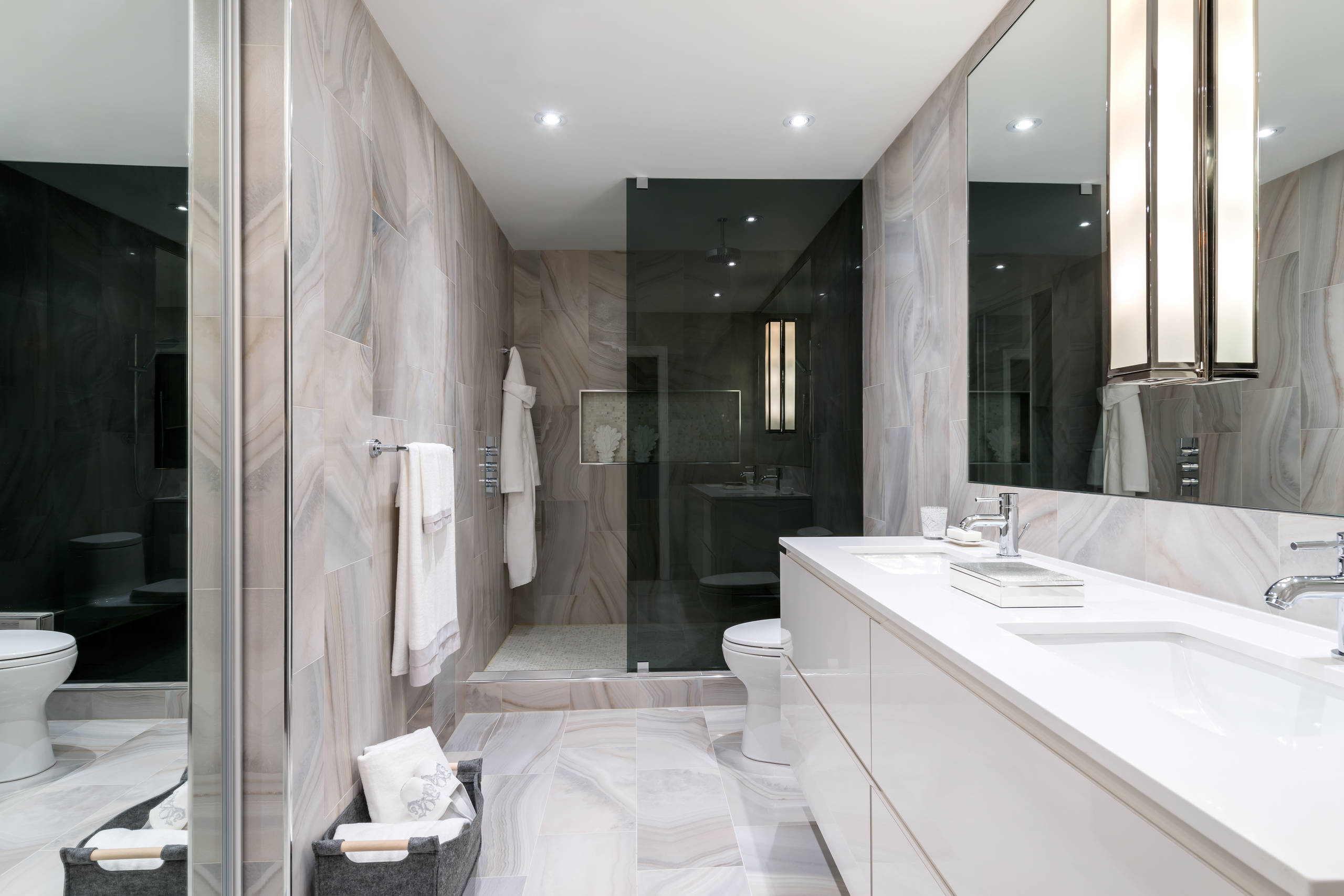 Luxurious bathroom with double vanity, walk-in shower, and marble-effect tiles.