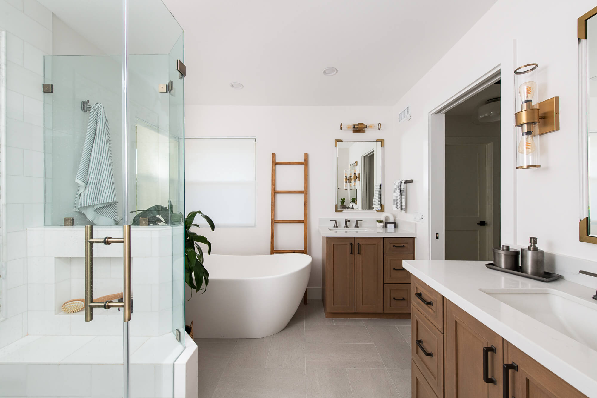 Modern bathroom with glass-enclosed shower, freestanding bathtub, and wooden vanities.