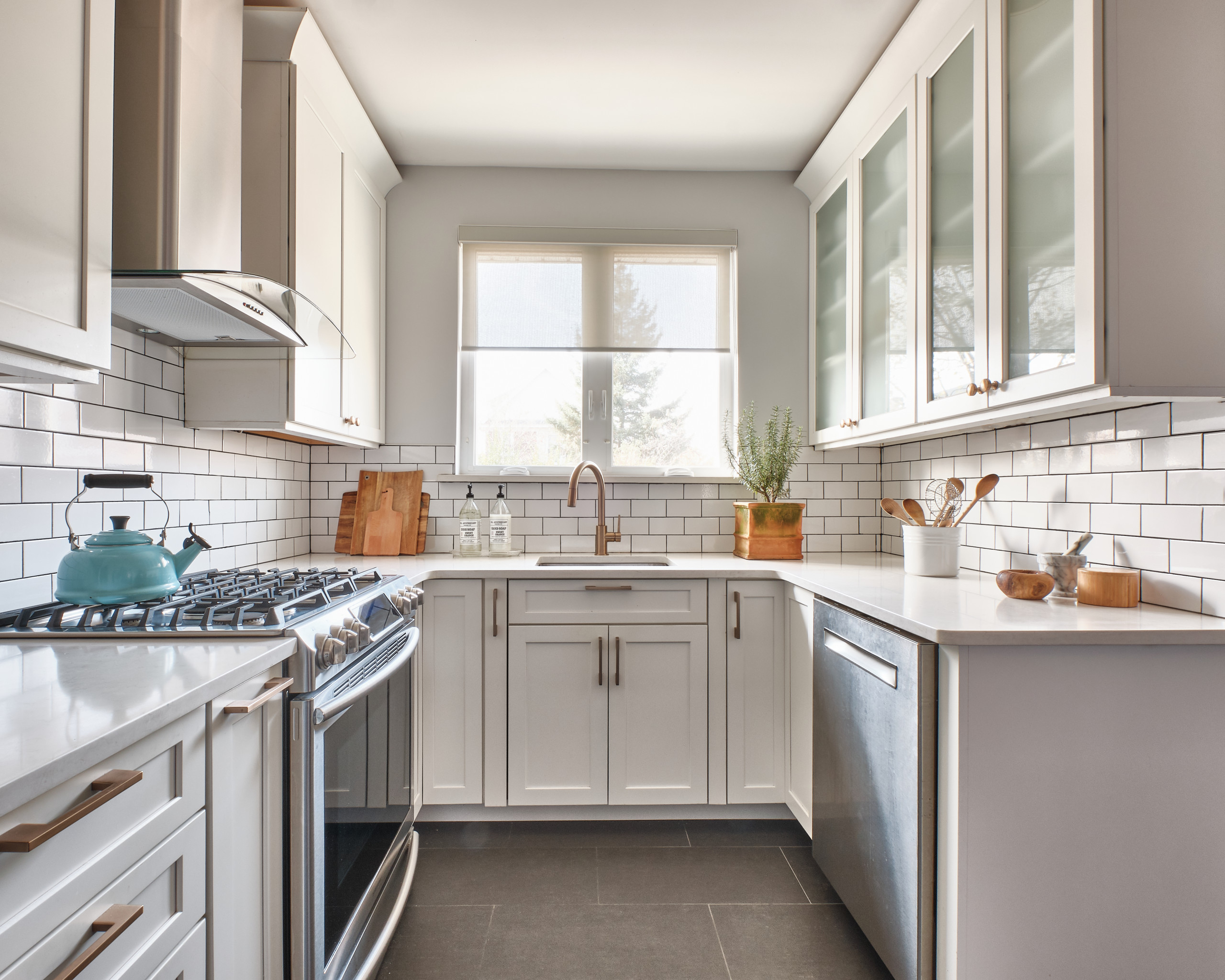 Modern U-shaped kitchen with white shaker cabinets, subway tile backsplash, and stainless steel appliances.