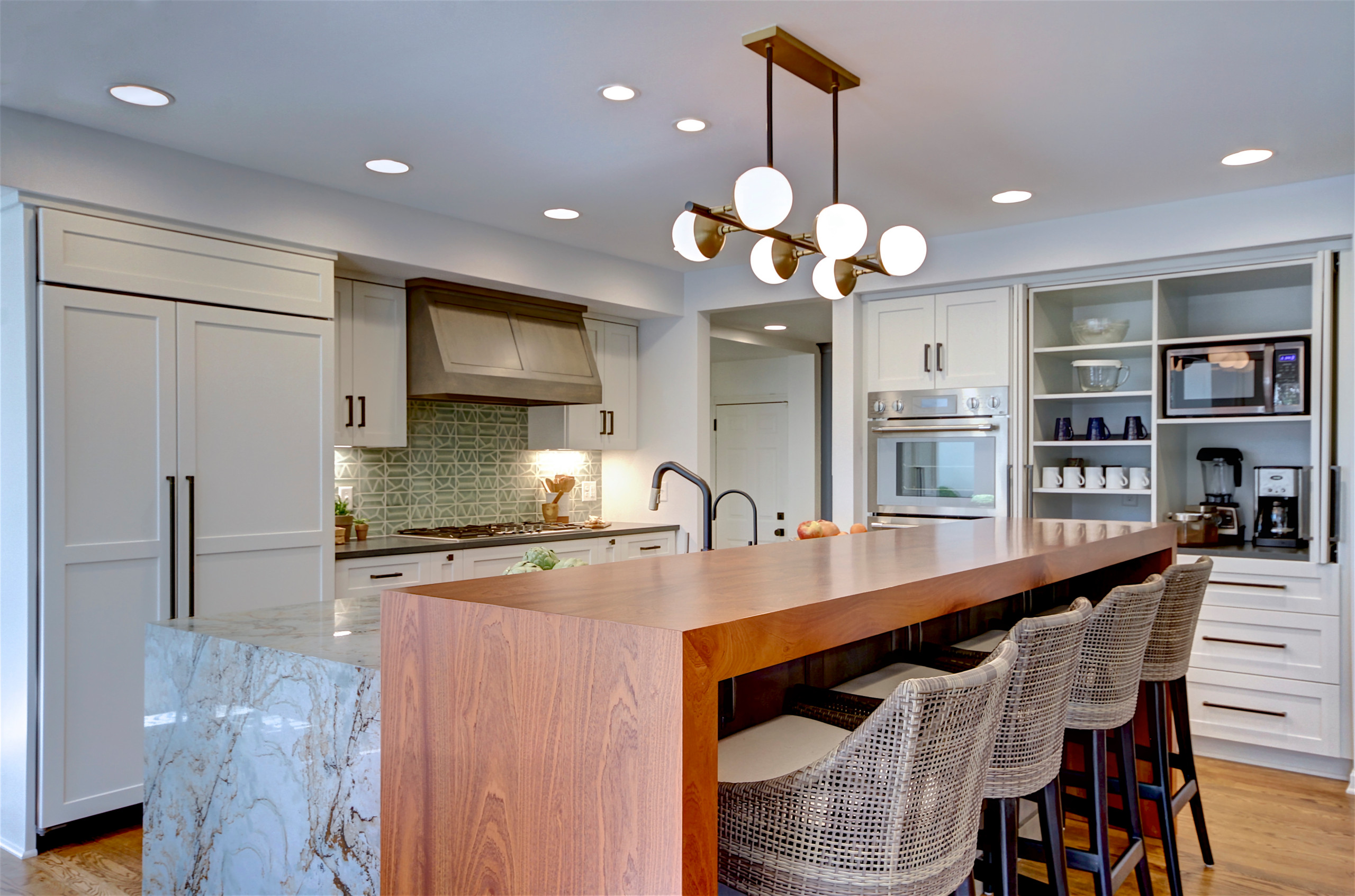 Modern kitchen with white cabinetry, wood waterfall island, and marble accents.
