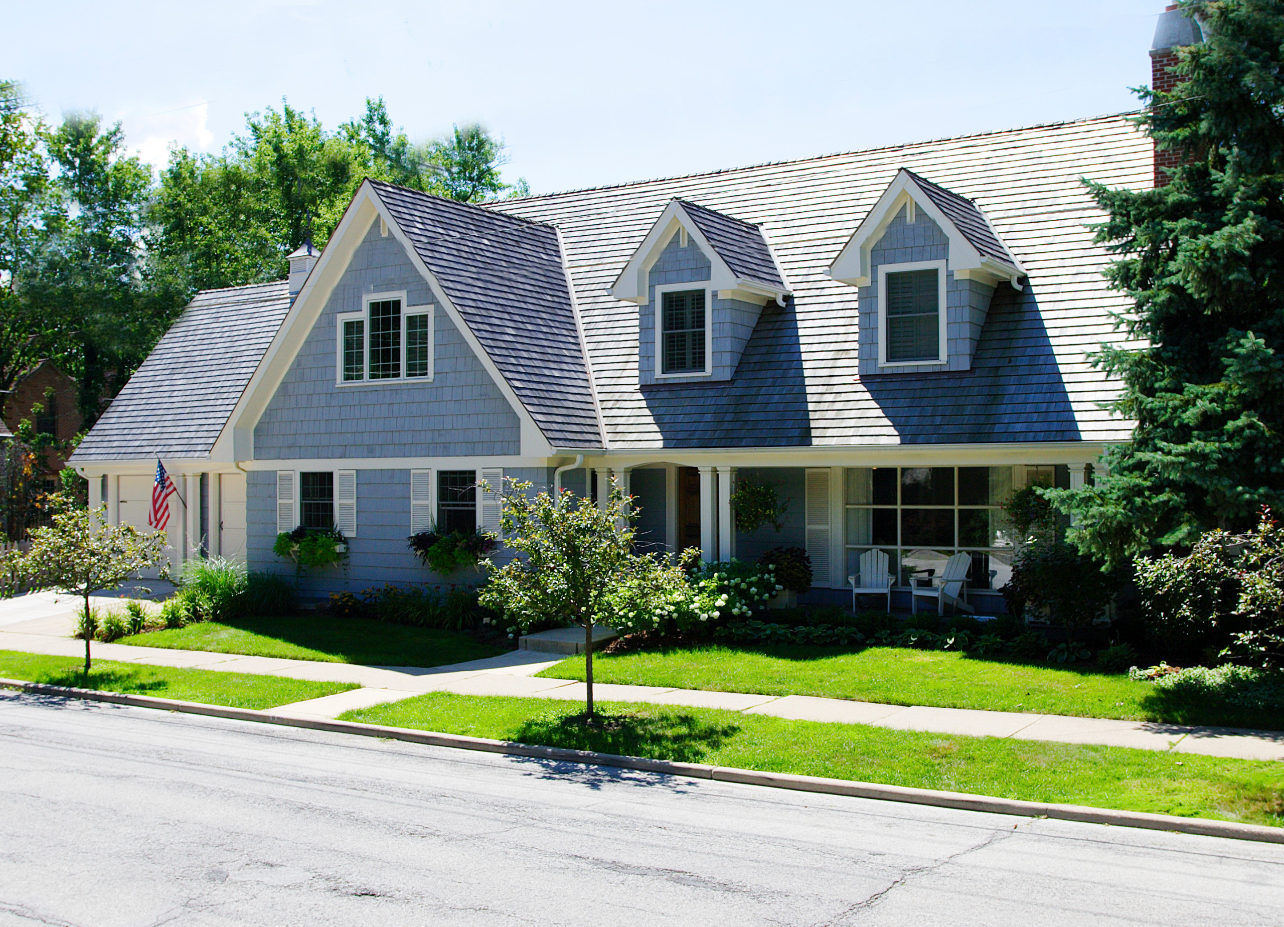 Two-story suburban home with blue siding, dormer windows, and a well-kept front yard.