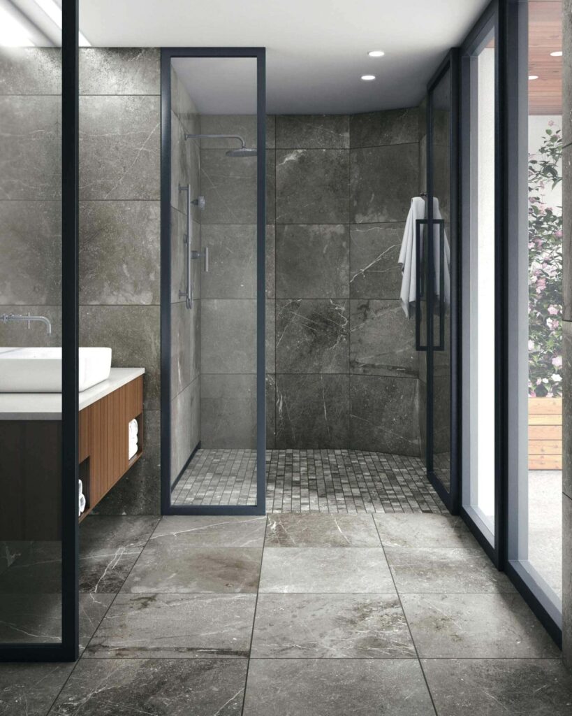 Modern walk-in shower with large gray stone tiles and glass enclosure