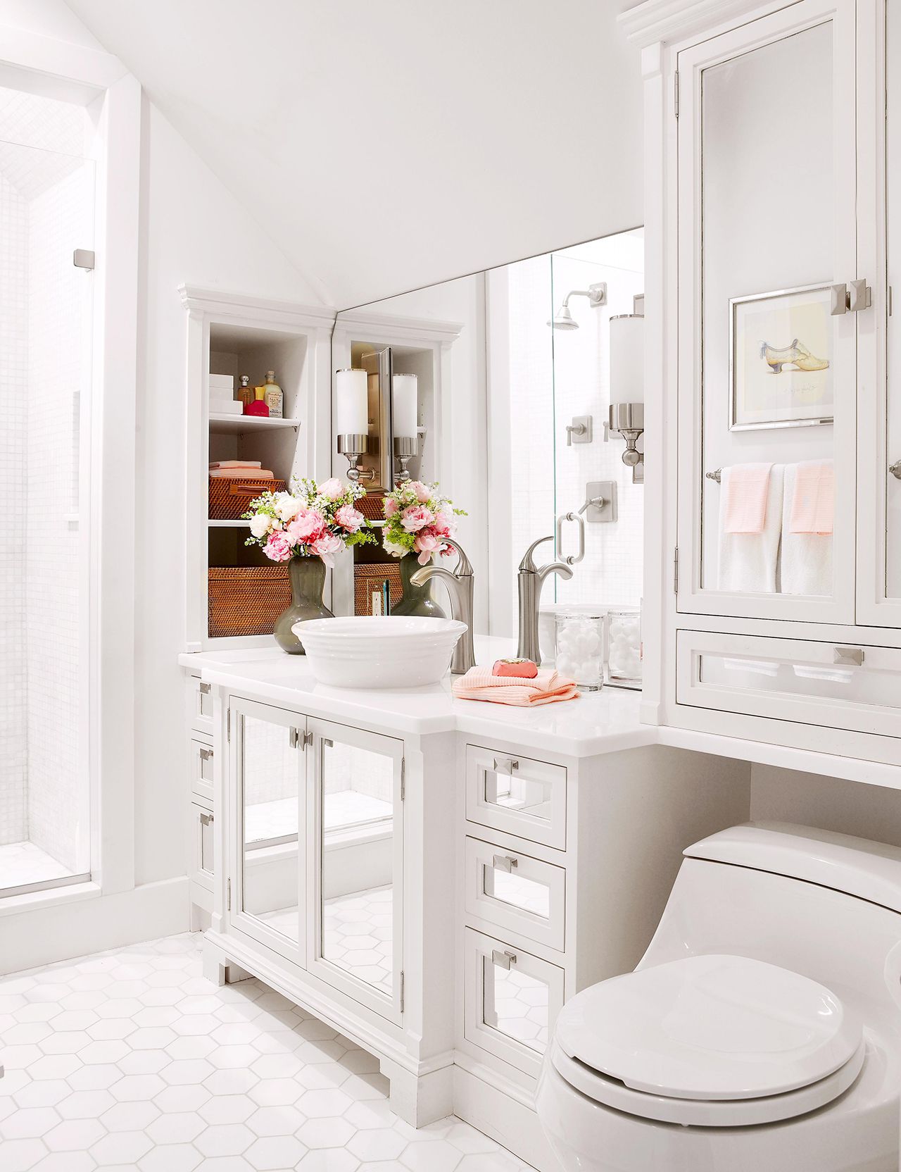 Compact white bathroom with mirrored cabinets, vessel sink, and fresh floral arrangement.