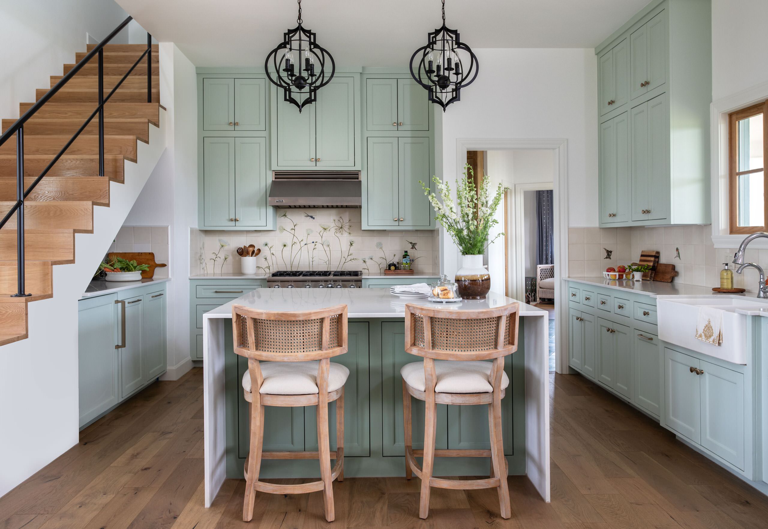 Charming farmhouse kitchen with sage green cabinets, wood accents, and floral backsplash.