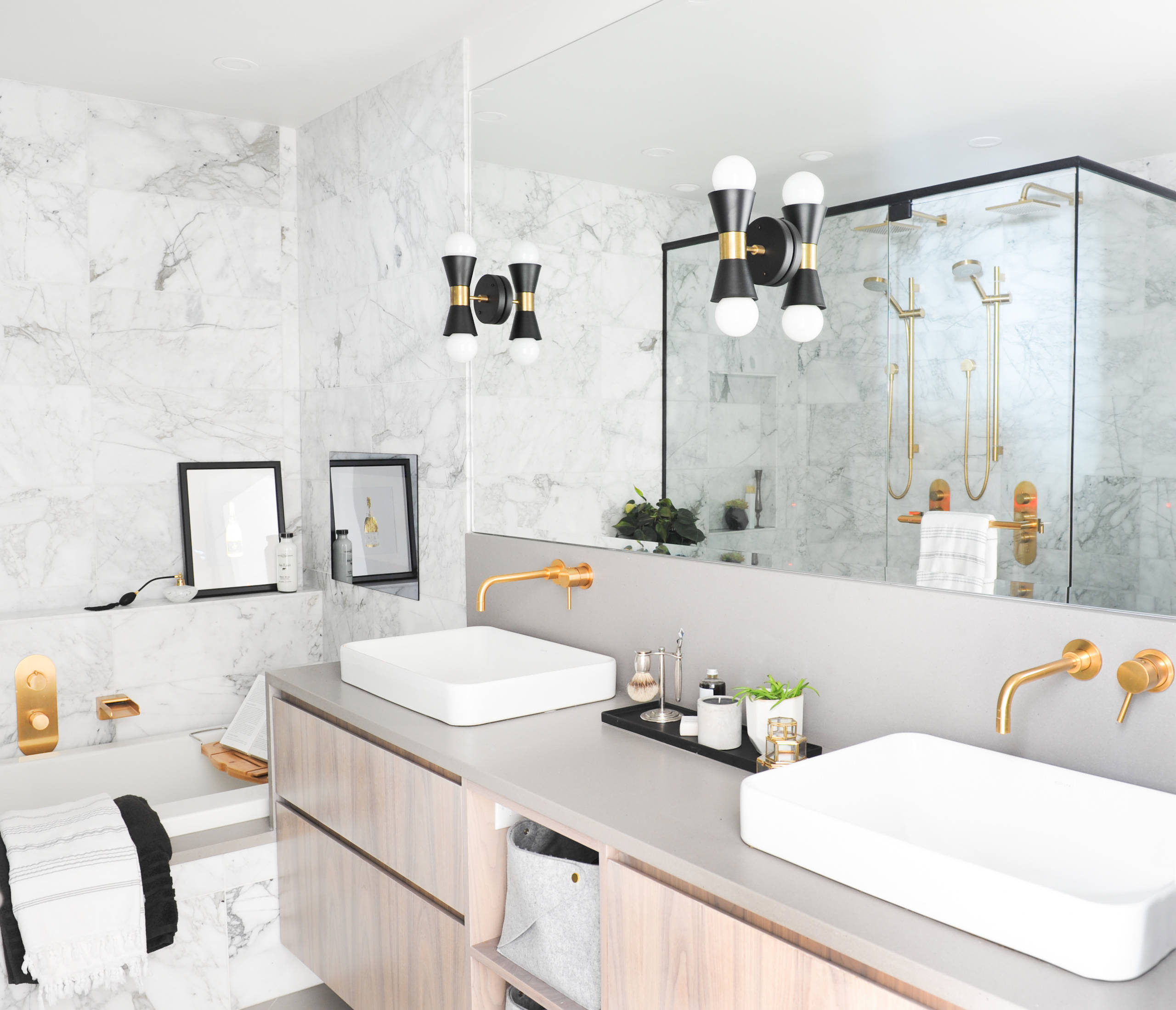 Modern bathroom with marble walls, double vanity, and gold fixtures.