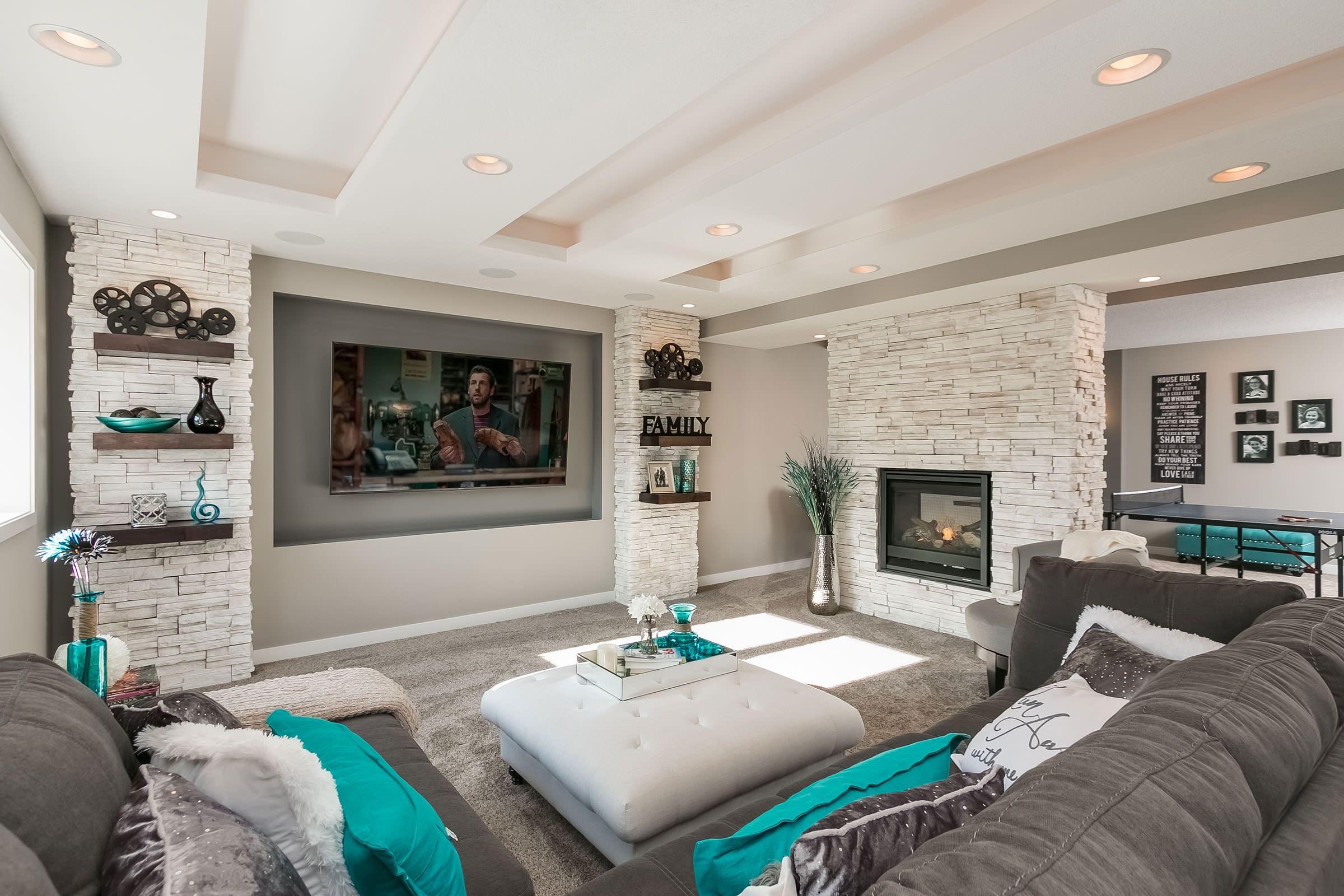 Basement living room with stone fireplace and home theater setup