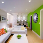 Colorful basement apartment with white furniture, green accent wall, and modern kitchenette.